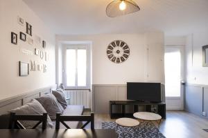 a living room with a couch and a clock on the wall at Le Nid Douillet ~ Confort ~ Parking ~ Terrasse in Saint-Chéron