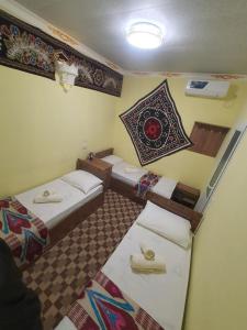 Zimmer mit 3 Betten und einer Wand mit einem Bild in der Unterkunft UMAR HOSTEL in Samarkand