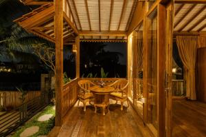 a wooden porch with a table and chairs on it at Oemah Cinta Ubud Villa in Ubud