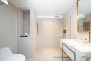 a white bathroom with a shower and a sink at Away Bangkok Riverside Kene in Bangkok