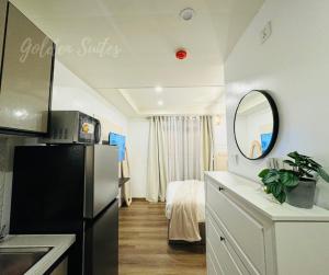 a kitchen with a black refrigerator and a bedroom at GOLDEN SUITES BAGUIO in Baguio