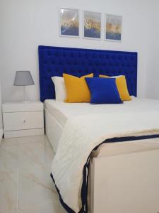 Madinaty Luxury Apartments New cairo في Madinaty: سرير مع وسائد صفراء و زرقاء في غرفة النوم