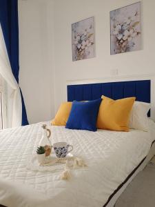 Madinaty Luxury Apartments New cairo في Madinaty: سرير أبيض مع اللوح الأمامي الأزرق والوسادة الزرقاء والأصفر