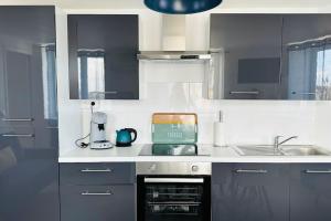 a kitchen with black and white cabinets and a sink at Duplex Chez Caro, 180m de la mer à Cayeux sur mer in Cayeux-sur-Mer +44 photos
