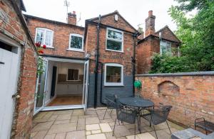 a patio with a table and chairs in front of a brick building at 2 Bedroom Home Full Of Character in Nantwich