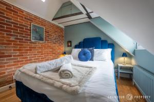 a bed with a blue headboard and a brick wall at The Blue House by Grandeur Property in Lymington