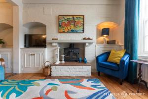 a living room with a blue chair and a fireplace at The Blue House by Grandeur Property in Lymington