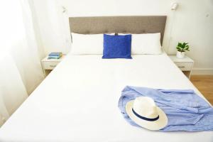 un letto bianco con un vestito blu e un cappello sopra di LaCassiopea a Donnalucata