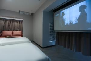 una camera con due letti e uno schermo di proiezione di Yunbo Youth Hostel Ürümqi a Ürümqi