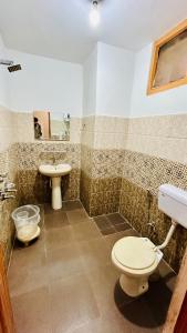 a bathroom with a toilet and a sink at Hotel New Ocean in Manāli