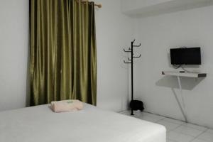 een slaapkamer met een wit bed en een televisie bij Cozy Home 2 RedPartner in Manado