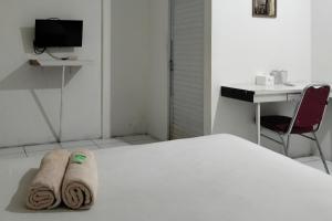 een slaapkamer met een bed, een bureau en een stoel bij Cozy Home 2 RedPartner in Manado