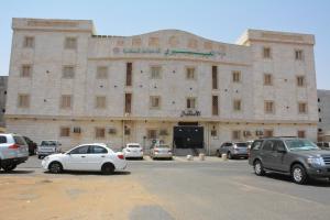 ein großes Gebäude mit Autos auf einem Parkplatz in der Unterkunft العيرى للشقق المخدومه جازان 1 in Dschāzān