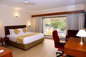 Habitación de hotel con cama, escritorio y ventana en Raj Park- Hill View, en Tirupati