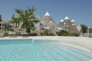 a villa with a swimming pool in front of a house at Trulli&Dimore - Casette Pricci in Castellana Grotte