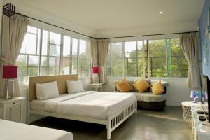 a bedroom with a bed and a couch and windows at BW Thai Art Style Hotel in Bangkok
