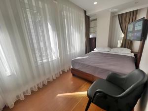 een slaapkamer met een bed, een stoel en ramen bij Genoa Port Hotel in Istanbul