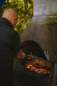 Ein Mann, der Essen im Außenofen kocht. in der Unterkunft Le chalet du bout du monde, en bord de rivière ! in Grez-sur-Loing