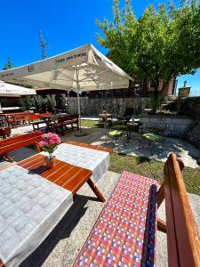 een patio met banken, tafels en een parasol bij Vikendica,Bungalovi Lipska pećina in Cetinje