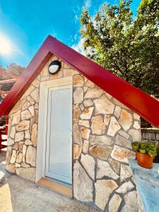 een stenen gebouw met een witte deur en een rood dak bij Vikendica,Bungalovi Lipska pećina in Cetinje