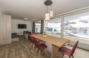 a dining room with a wooden table and red chairs at Adler Resort in Saalbach Hinterglemm