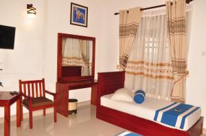 een slaapkamer met een bed, een bureau en een spiegel bij Nature First Hotel in Nuwara Eliya