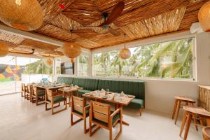 a restaurant with wooden tables and chairs and a green couch at Samawa Living in Paje