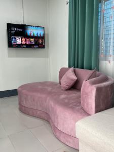 a large pink couch in a room with a tv at Pani House Hatyai 4 in Hat Yai