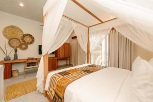 a bedroom with a canopy bed and a desk at Samawa Living in Paje