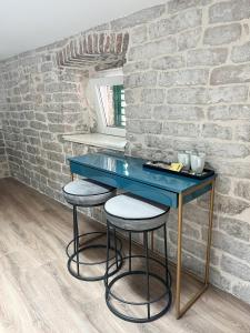 une table bleue et des tabourets dans une pièce avec un mur en briques dans l'établissement Centrum Luxury Rooms, à Šibenik