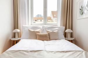 Bett mit weißer Bettwäsche und Kissen vor einem Fenster in der Unterkunft Sage Apartment Old Town Bratislava in Bratislava