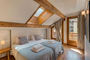 Duas camas num quarto com tectos e janelas em madeira em Les Melées Apartments - Alpes Travel - Argentiere em Chamonix-Mont-Blanc