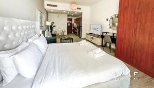 a bedroom with a large white bed and a living room at RARE Holiday Homes - Near the Mall - Stylish - Crescent Tower - IMPZ - R705 in Dubai