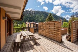 um deque de madeira com uma mesa de piquenique de madeira e montanhas em Les Melées Apartments - Alpes Travel - Argentiere em Chamonix-Mont-Blanc
