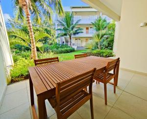 a wooden table and chairs in a patio with palm trees at Apartment in a Tropical Oasis, Ki Residences, Pereybere in Pereybere