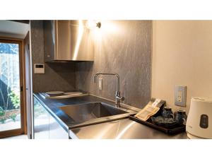 eine Küche mit einer Spüle aus Edelstahl und einer Theke in der Unterkunft Kominka Hotel kurasu - Vacation STAY 24275v in Tatsuno