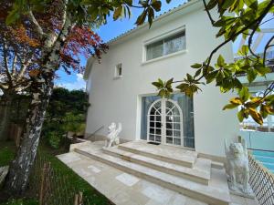 a white house with two cats sitting on the stairs at Villa face mer in Royan