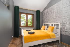 sypialnia z łóżkiem z żółtą pościelą i oknem w obiekcie Golden Villa Saska Kępa w Warszawie