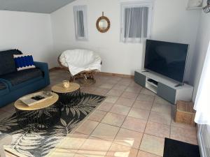 sala de estar con sofá azul y TV en Charmante Maison La Tranche sur Mer 100 m de la plage, en La Tranche-sur-Mer