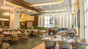 un comedor con mesas, sillas y ventanas en Babylon Rotana Hotel, en Baghdād
