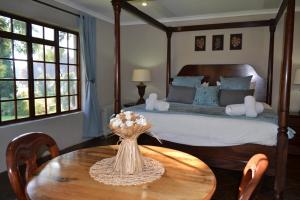 Un dormitorio con una cama y una mesa con flores. en Remi Lodge, en Dullstroom
