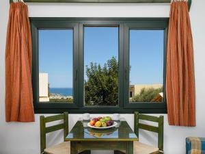 a table with a bowl of fruit in front of a window at Elen-Mari in Hersonissos