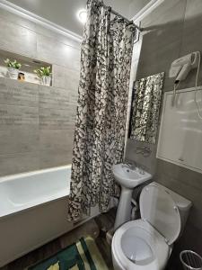 een badkamer met een toilet en een douchegordijn bij Бектурова 15 in Pavlodar