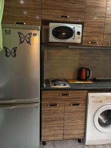 een keuken met een koelkast en een magnetron bij Бектурова 15 in Pavlodar