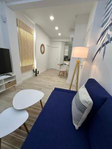 Una sala de estar con un sofá azul y un televisor. en Apartamento Andalucía 33 Izquierda, en Málaga