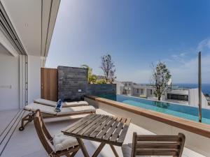 Un balcón con mesa y sillas y una piscina. en Aquasuites Luxury Apartament B08, en Acantilado de los Gigantes
