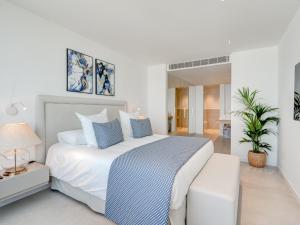 Un dormitorio blanco con una cama grande con almohadas azules. en Aquasuites Luxury Apartament B07, en Acantilado de los Gigantes 16 fotos más