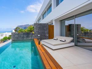 Una casa con piscina y una cama en un balcón. en Aquasuites Luxury Apartament B07, en Acantilado de los Gigantes