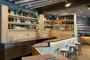 a kitchen with a bar with stools and bottles at HUNURIJÄRVI RESORT***** in Härmä