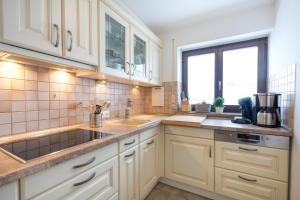 a kitchen with white cabinets and a sink and a window at Ferienwohnung Almwiesen in Obermaiselstein +5 photos